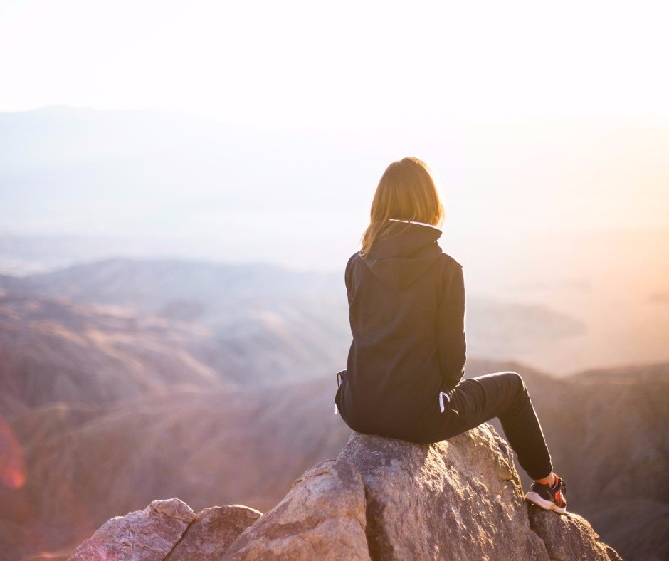 Woman sitting on top of mountain. If you want to change your life, you can.